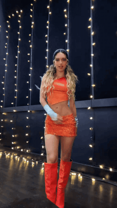 A Woman In An Orange Dress And Red Boots GIF