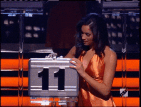 A Woman In An Orange Dress Holds A Briefcase With The Number 11 On It GIF