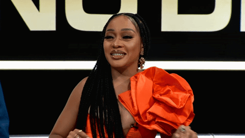 A Woman In An Orange Dress Stands In Front Of A Sign That Says Ncj GIF