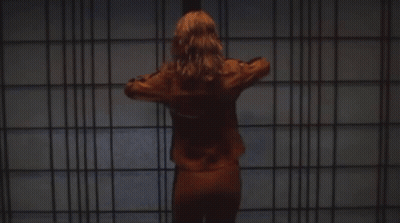 A Woman In An Orange Jacket Is Holding A Knife GIF