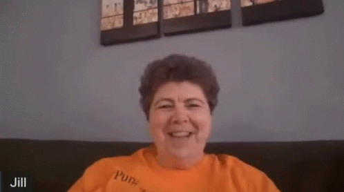A Woman In An Orange Shirt Is Making A Funny Face And Says Oops GIF