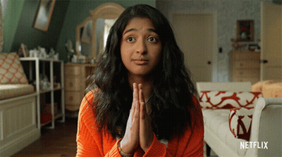 A Woman In An Orange Sweater Is Praying With Netflix Written On The Bottom Right GIF
