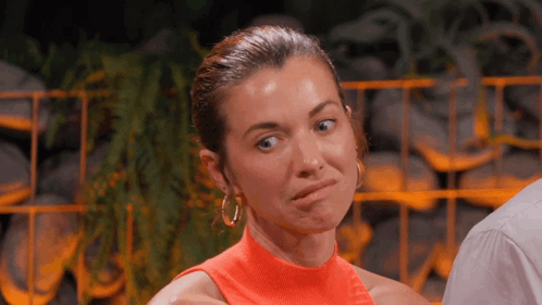 A Woman In An Orange Top Is Making A Face GIF