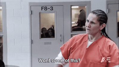 A Woman In An Orange Uniform Is Standing In Front Of A Door That Says F8-3 On It . GIF