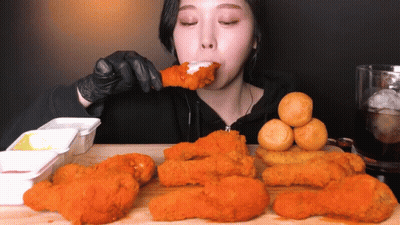A Woman In Black Gloves Is Eating Fried Food GIF