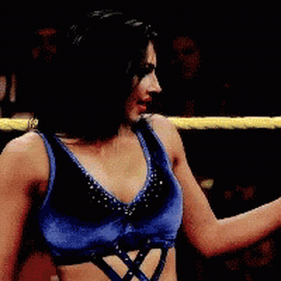 A Woman In Blue Shorts Is Standing In A Wrestling Ring With Another Woman GIF