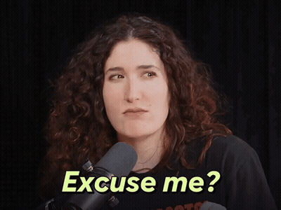 A Woman In Front Of A Microphone With The Words " Excuse Me " On Her Face GIF