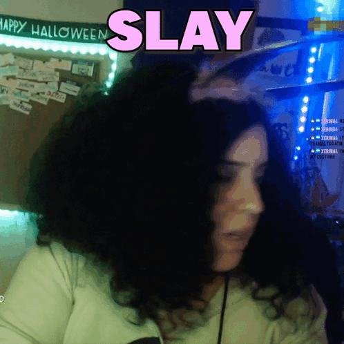 A Woman In Front Of A Sign That Says Happy Halloween And Says Slay GIF