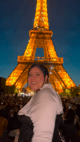 A Woman In Front Of The Eiffel Tower At Night GIF