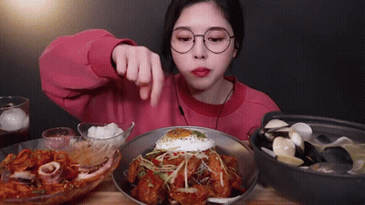 a woman in glasses is eating a plate of food with a fried egg on top