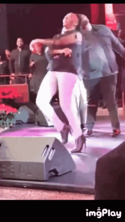 A Woman In High Heels Is Dancing On A Stage With A Man GIF