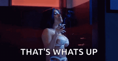 A Woman In Lingerie Is Smoking A Cigarette In A Dark Room . GIF