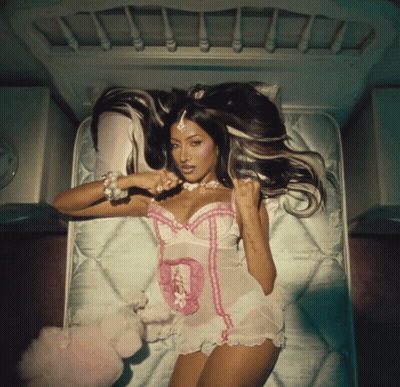 A Woman In Lingerie Laying On A Bed With A Teddy Bear GIF