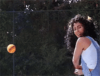 A Woman In Overalls Is Holding A Tennis Ball In Her Hand GIF