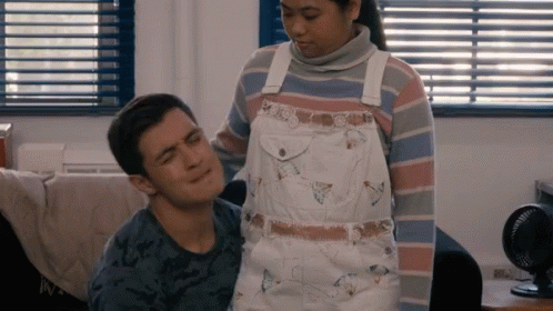 A Woman In Overalls Stands Next To A Man GIF