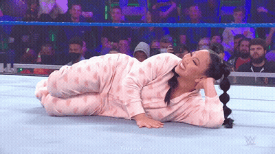 A Woman In Pink Pajamas Is Laying On The Ground In A Wrestling Ring . GIF