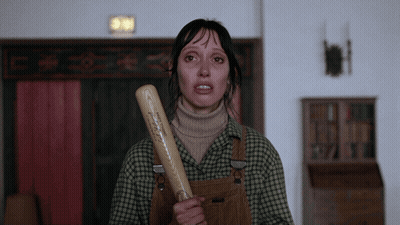 A Woman In Plaid Overalls Is Holding A Baseball Bat With A Sticker On It That Says ' A ' On It GIF