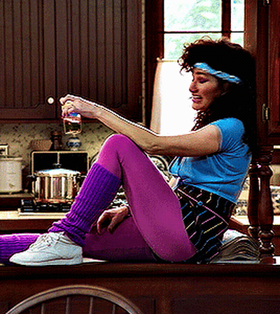 A Woman In Purple Leg Warmers Is Sitting On A Counter GIF