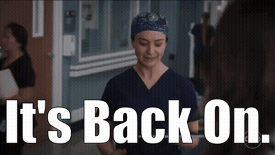 A Woman In Scrubs Is Standing In A Hallway With The Words " It 'S Back On " Above Her GIF