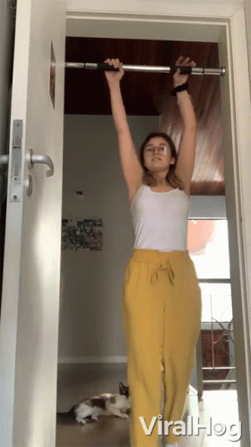 A Woman In Yellow Pants Is Doing Pull Ups On A Bar GIF