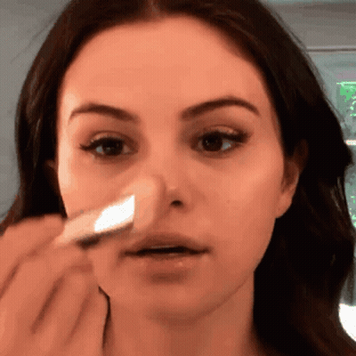 A Woman Is Applying A Sponge To Her Nose GIF