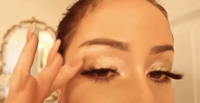 A Woman Is Applying Eye Shadow To Her Eye . GIF