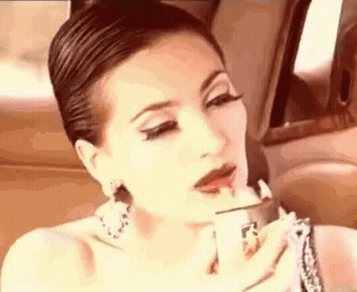 A Woman Is Applying Lipstick In A Car While Sitting In The Back Seat . GIF