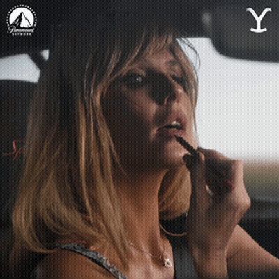 A Woman Is Applying Lipstick In A Car With A Paramount Network Logo GIF