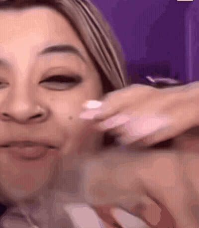 A Woman Is Applying Lotion To Her Face And Smiling GIF