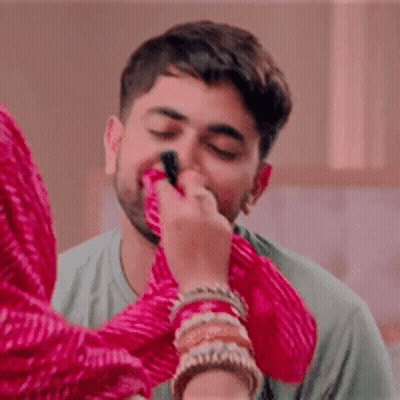 A Woman Is Applying Makeup To A Man 'S Face With A Brush . GIF