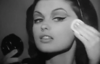 A Woman Is Applying Makeup To Her Face With A Sponge . GIF