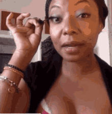 A Woman Is Applying Mascara To Her Eyelashes And Looking At The Camera . GIF
