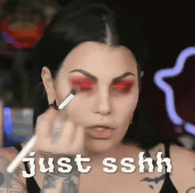 A Woman Is Applying Red Eye Shadow To Her Eyes . GIF