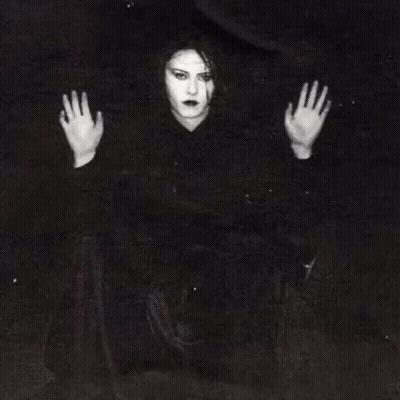 A Woman Is Behind Bars In A Jail Cell With Her Hands Behind The Bars . GIF