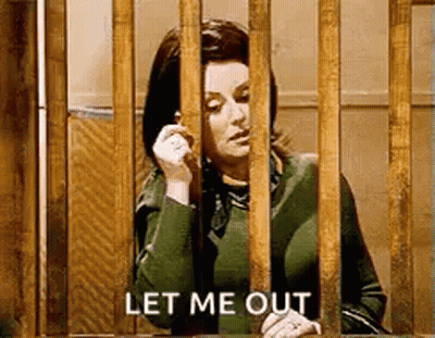 A Woman Is Behind Bars Talking On A Cell Phone And Says `` Let Me Out '' . GIF