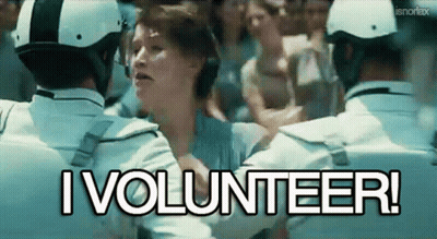 A Woman Is Being Held By A Group Of Police Officers With The Words I Volunteer Written Above Her GIF