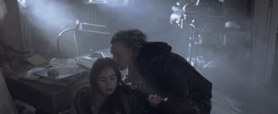 A Woman Is Being Held By A Man In A Dark Room GIF