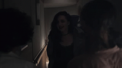 A Woman Is Being Held By Another Woman In A Dark Hallway GIF