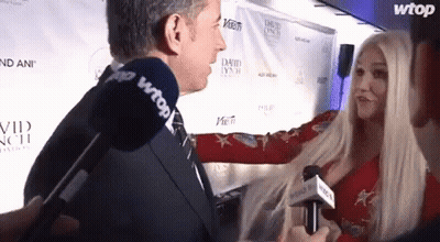 A Woman Is Being Interviewed By A Man With A Microphone That Says Wtop On It GIF