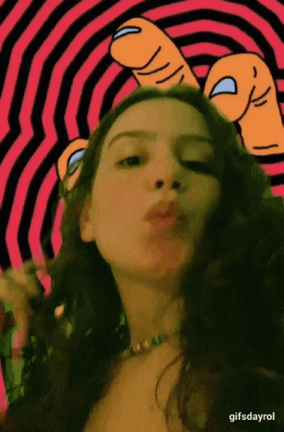 A Woman Is Blowing A Kiss In Front Of A Pink And Black Striped Background .. GIF