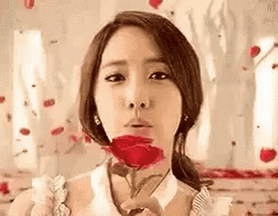 A Woman Is Blowing A Kiss While Holding A Red Rose . GIF