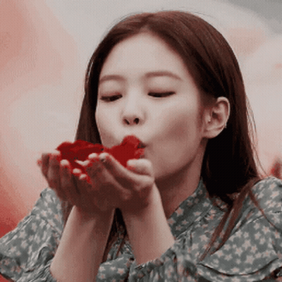 A Woman Is Blowing A Red Heart Out Of Her Hand GIF
