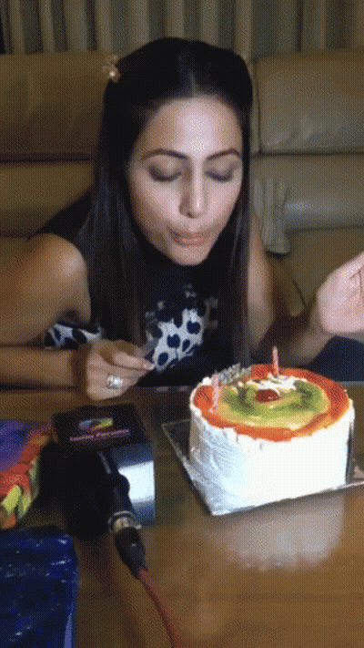 A Woman Is Blowing Out A Candle On A Cake GIF