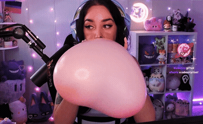 A Woman Is Blowing Up A Pink Balloon In Front Of A Microphone .. GIF