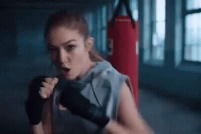 A Woman Is Boxing In A Gym With A Red Punching Bag . GIF