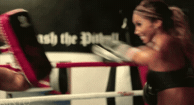 A Woman Is Boxing In A Ring With A Sign Behind Her That Says " Ash The Dust " GIF