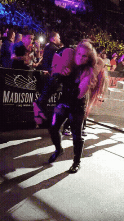 A Woman Is Carrying Another Woman On Her Shoulders In Front Of A Madison Sign GIF