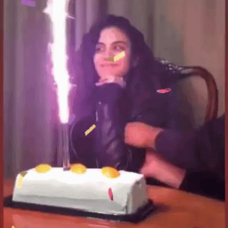 A Woman Is Celebrating Her Birthday With A Cake And Candles GIF