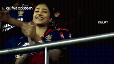 A Woman Is Clapping Her Hands In The Stands During A Cricket Game . GIF
