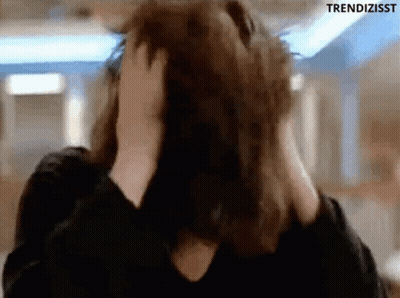 A Woman Is Covering Her Ears With Her Hands While Looking At The Camera . GIF
